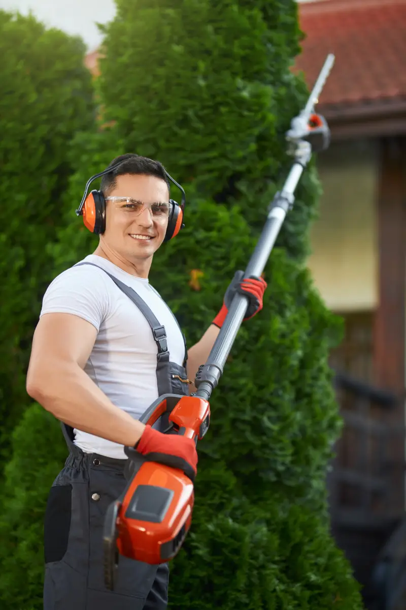 smiling-gardener-holding-petrol-hedge-cutter-outdoors